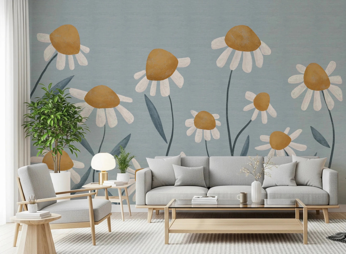 Sunny Daisy Field wallpaper mural with painted daisies on blue behind a grey sofa and matching armchair in a living room