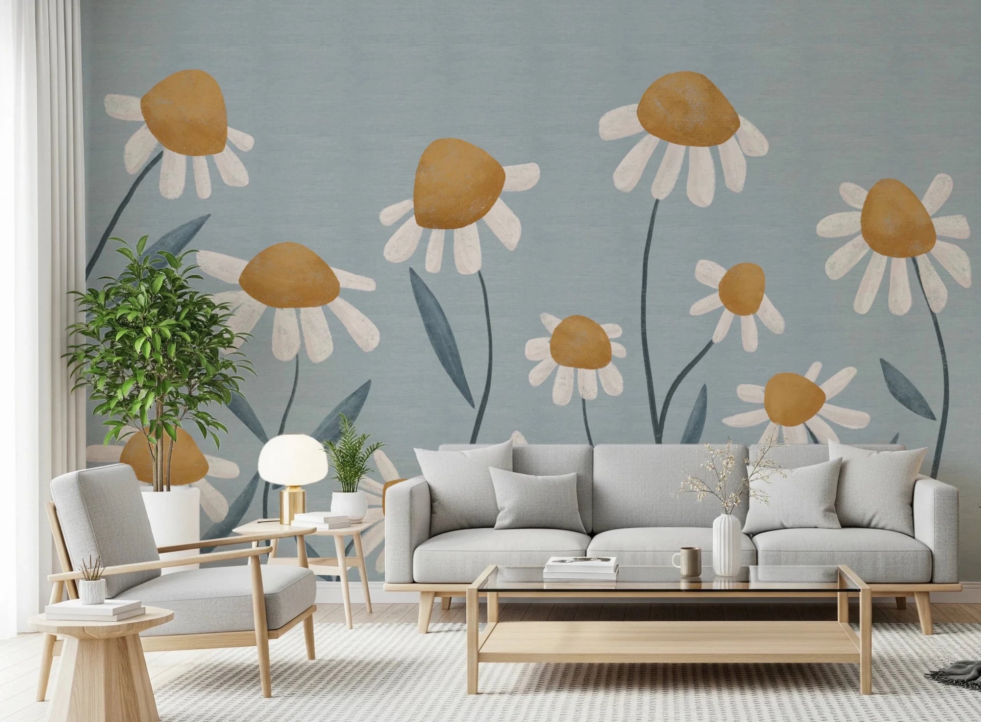 Sunny Daisy Field wallpaper mural with painted daisies on blue behind a grey sofa and matching armchair in a living room