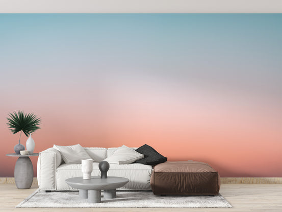Sunrise Sky Gradient Serenity wallpaper mural in blue and coral behind a white sofa and brown ottoman in a living room