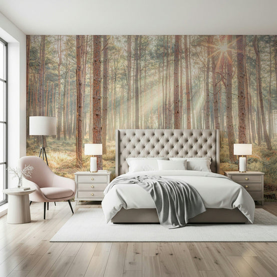 Sunrise's Kiss in the Misty Forest wallpaper mural of sunlit pines behind a grey tufted bed and pink chair
