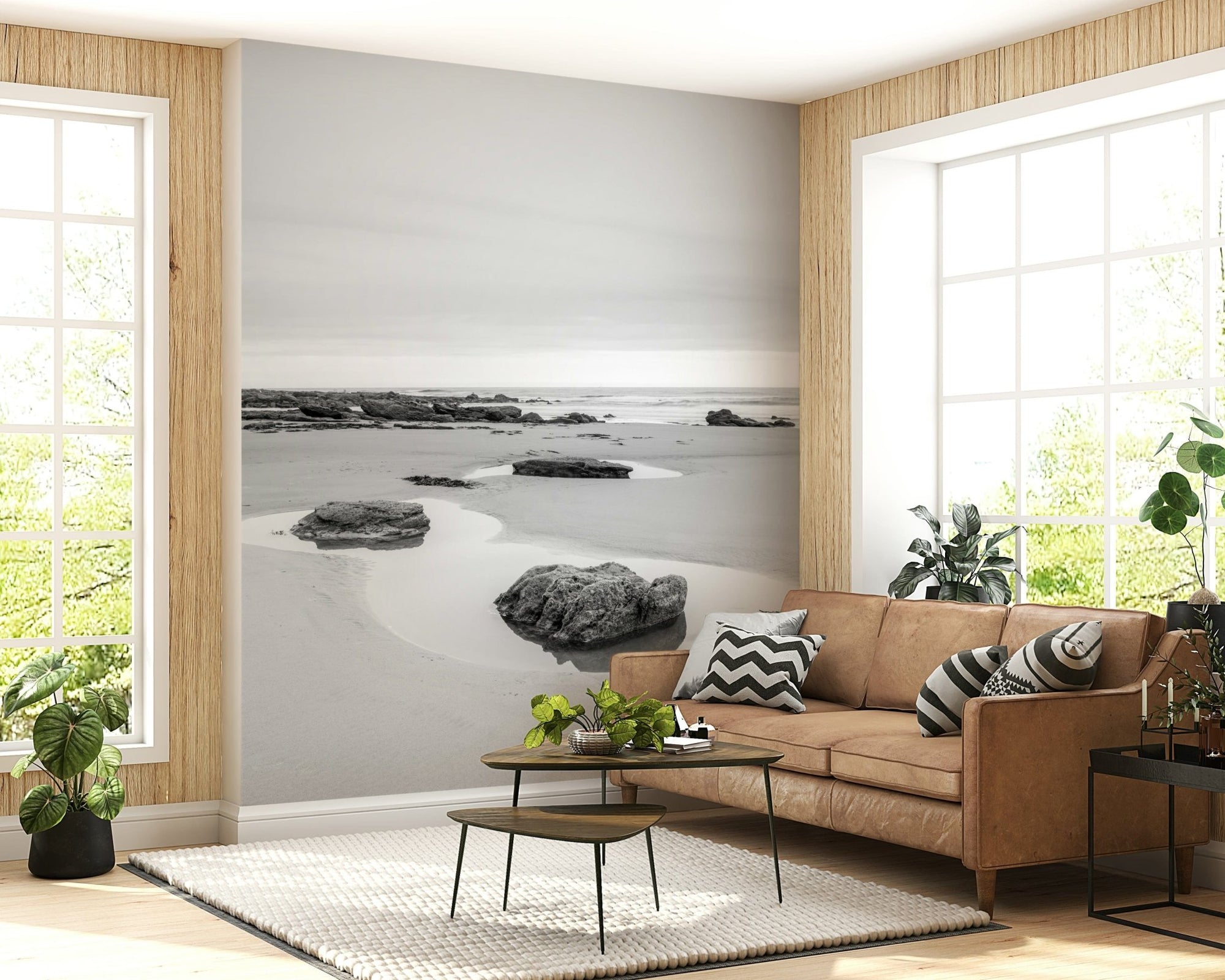 Tide Pools black and white wall mural of rocks on pale sand behind a tan leather sofa in a bright living room