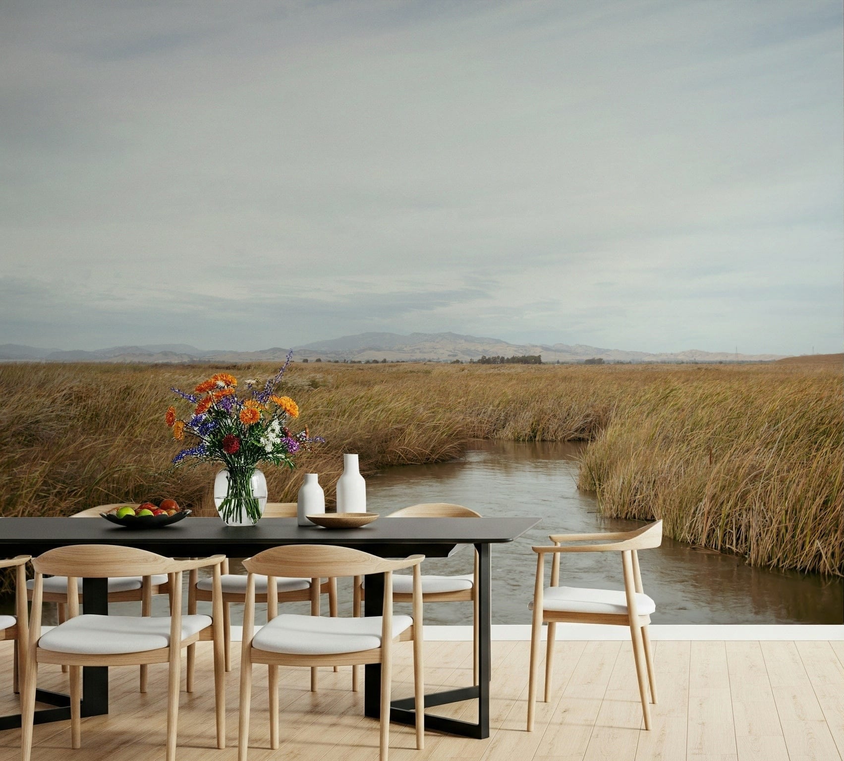 Tranquil Marsh View wallpaper mural of a golden reed marsh and water channel in a dining room with black table and wood chairs
