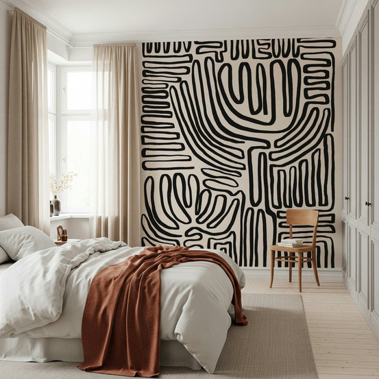 Tribal Echo wallpaper mural with black squiggly lines on cream behind a white bed with a rust throw