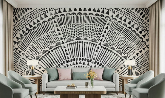 Tribal Half Sun wallpaper mural in black and white behind a white sofa and sage armchairs in a living room
