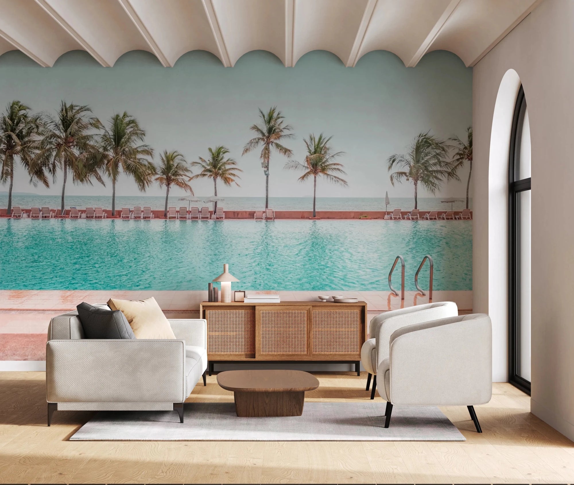 Tropical Poolside wallpaper mural of a turquoise resort pool and palm trees above a white sofa and rattan sideboard