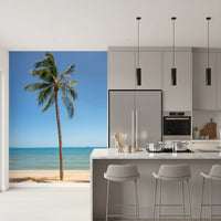 Tropical Retreat wallpaper mural of a palm on a sandy beach beside a white marble kitchen island and stools