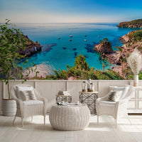 Turquoise Cove Escape wallpaper mural of the bay behind two white wicker armchairs on a terrace