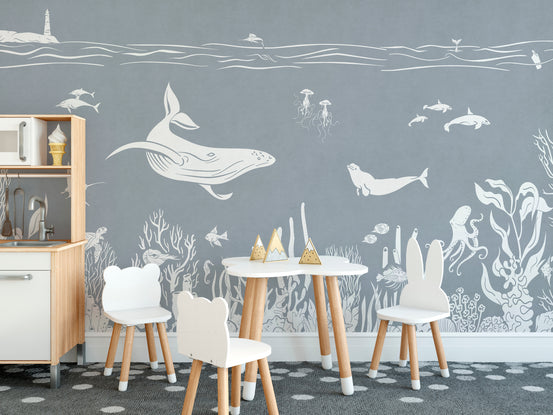 Monochrome Sea Blue wallpaper mural with white line-art whales and coral in a kids room with bear-ear chairs