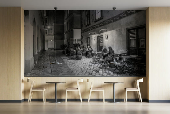 Street cafe in Vienna wallpaper mural, black and white cobbled alley and cafe diners, above wood chairs and bistro tables