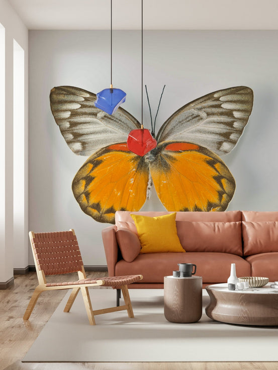 Whimsical Butterfly wallpaper mural of a large orange and grey butterfly above a rust leather sofa in a living room