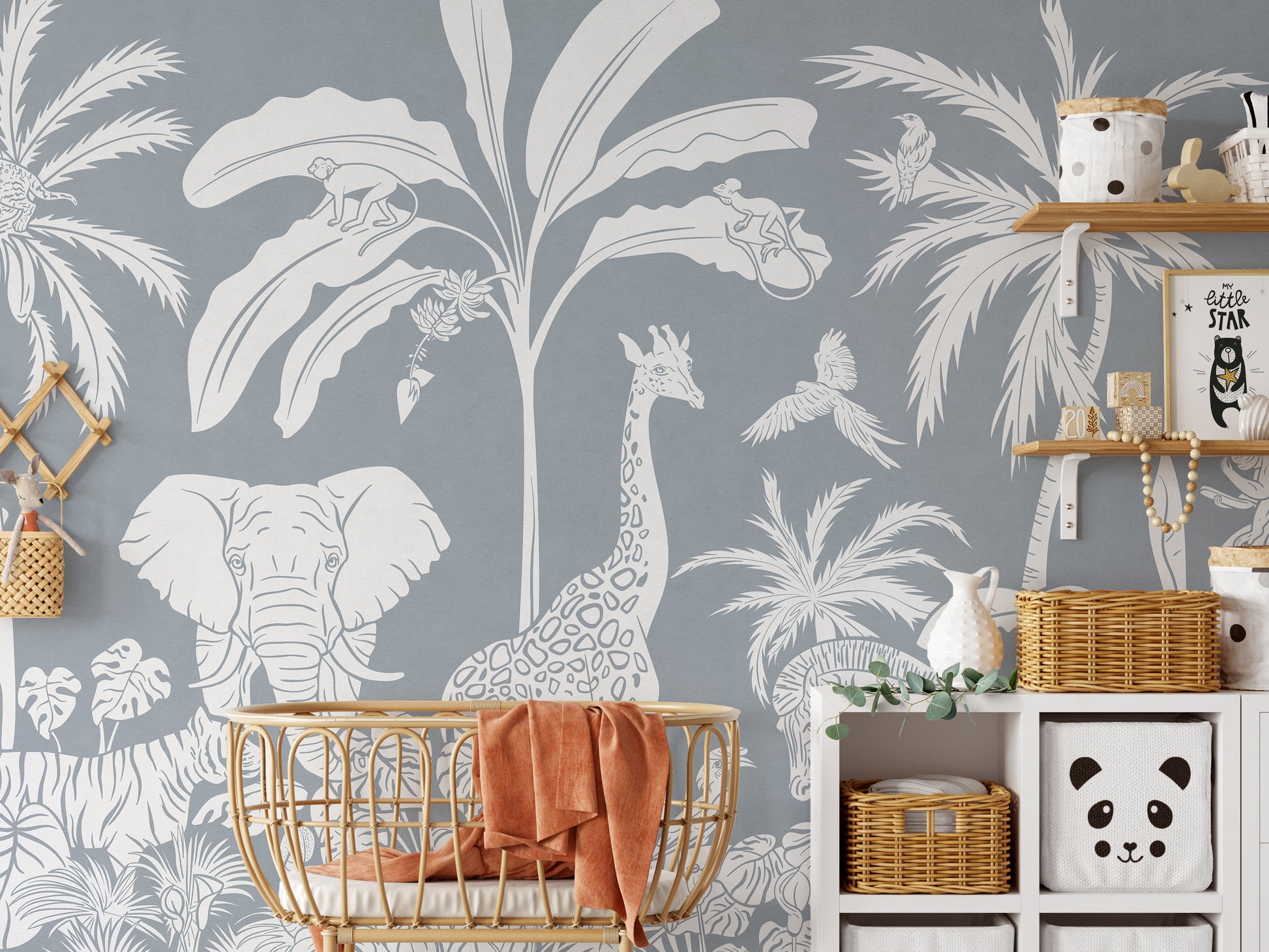 Removable self adhesive Monochrome Jungle Blue Wall Mural in a nursery with a rattan crib and storage shelving.