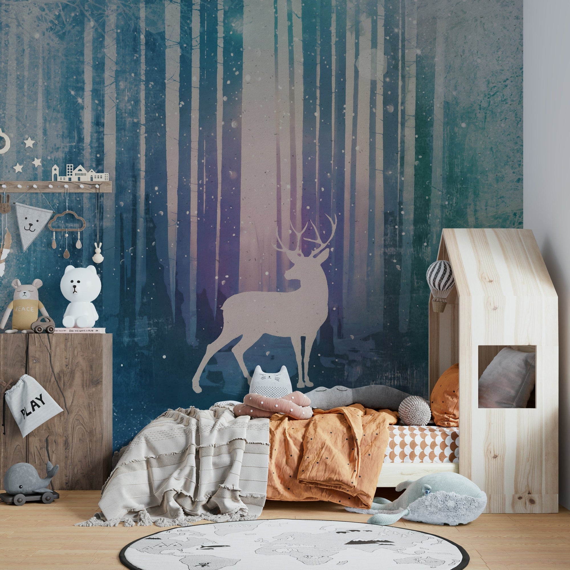 Silent Winter Woods wallpaper mural with a beige stag in a teal snowy forest above a child's bed in a nursery