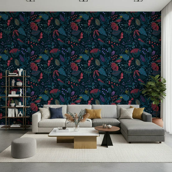Wonderforest wallpaper with dark navy florals and birds behind a grey sectional sofa and bookshelf in a living room